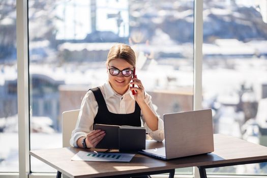 Successful woman mentor, director, businessman in glasses and a suit is studying documents, sitting at the table. Working day concept