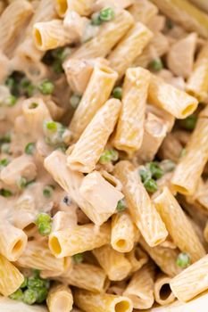Mixing ingredients in an enameled dutch oven to prepare chicken alfredo pasta.
