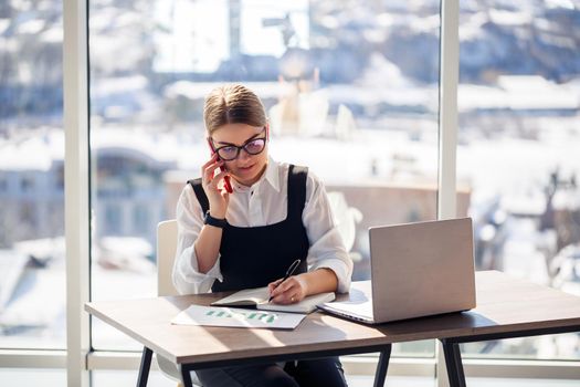 Successful woman mentor, director, businessman in glasses and a suit is studying documents, sitting at the table. Working day concept