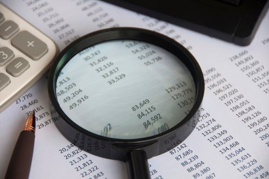 Business analysis concept - magnifying glass with calculator and number analysis background. Copy space.
