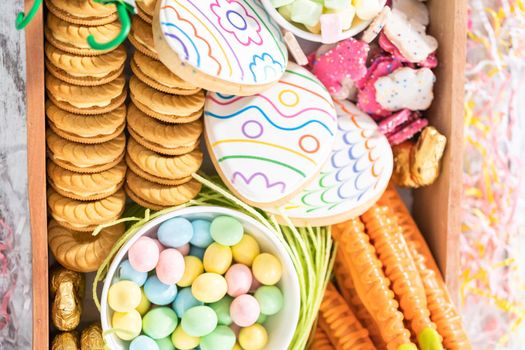 Assembling charcuterie board with Easter candies, cookies, and marshmallows.