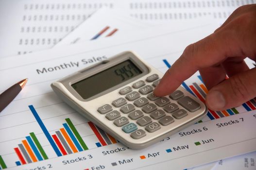 Hand pressing calculator with graph analysis background. Business analysis concept.