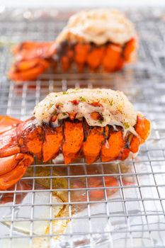 Buttering lobster tails on a baking sheet with kitchen foil.