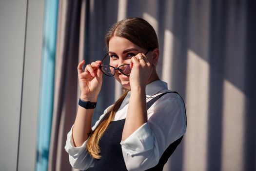 Confident business woman boss standing in modern office wearing glasses, female leader, business owner thinking about future success, planning new opportunities