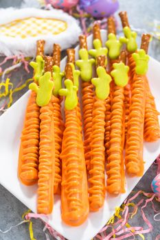 Carrot chocolate-covered pretzels on a white serving plate for the Easter table.