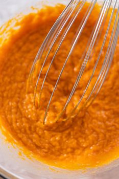 Mixing ingredients in a glass mixing bowl to bake sweet pumpkin bread.