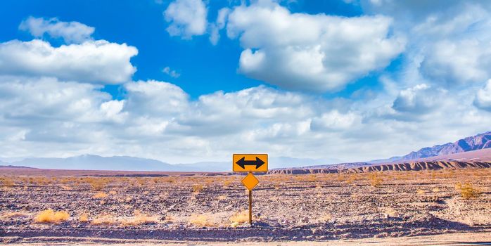 Directional sign in the desert with scenic blue sky and wide horizon. Concept for trip, freedom, holiday and transportation.