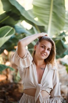 A woman stands near green banana leaves on the island. Tropical trees