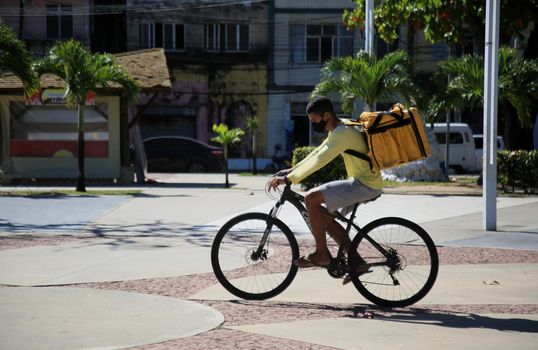 Jovem com uma mochila entregando comida em uma bicicleta na cidade de Salvador, nessa sexta-feira (13) (Joá Souza/ Futura Press).
