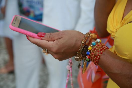 salvador, bahia, brazil - december 8, 2021: hand with bracelets holding on a cell phone in the city of Salvador.
