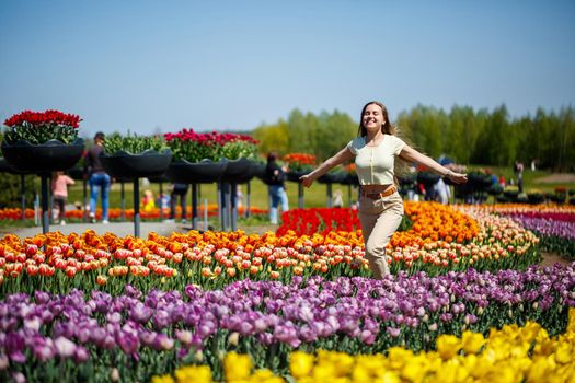 A girl in a white dress runs among the tulips. Field with yellow and red tulips.