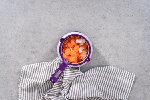 Flat lay. Melting color chocolate chips in a candy melting pot to make carrot chocolate-covered pretzels.