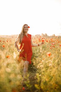 A woman of European appearance with long blonde hair and a red summer dress, she stands in a blooming poppy field