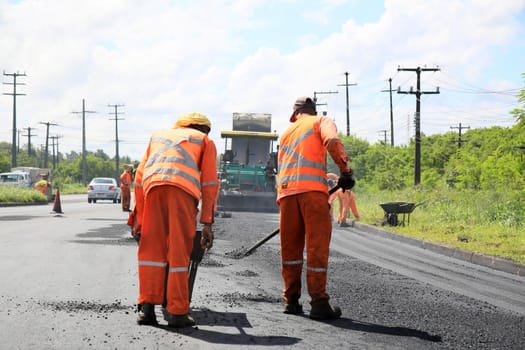 camacari, bahia, brazil - august 24, 2021: workers are seen doing asphalt recap of the access lane to the industrial hub of the city of Camacari.