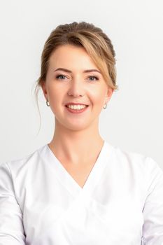 Close-up portrait of young smiling female caucasian healthcare worker standing staring at the camera on white background