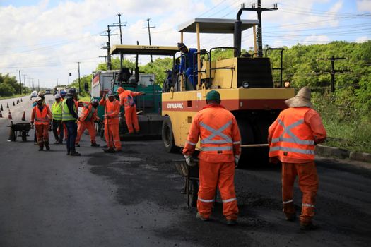 camacari, bahia, brazil - august 24, 2021: workers are seen doing asphalt recap of the access lane to the industrial hub of the city of Camacari.