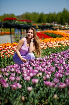 A young woman in a pink suit stands in a blooming field of tulips. Spring time