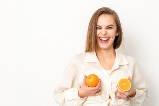 Young Caucasian smiling woman holding slices orange over isolated white background, breast health concept