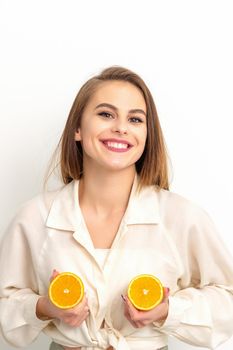 Young Caucasian smiling woman holding slices orange over isolated white background, breast health concept