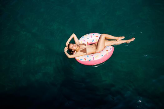 Young woman in a swimsuit swims on an inflatable ring in the sea. Summer vacation concept.