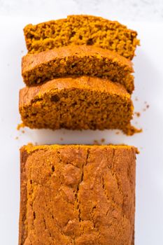 Sliced homemade pumpkin bread on a white cutting board.