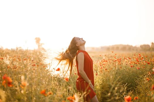 Beautiful woman in a red dress in a field of blooming poppies. Selective focus