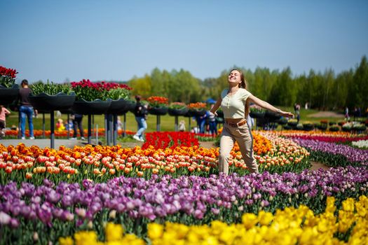 A girl in a white dress runs among the tulips. Field with yellow and red tulips.