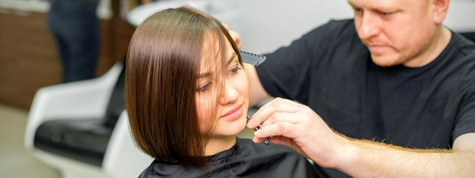 Haircut of short hair of young caucasian woman by a male hairdresser in a barbershop