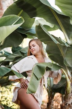 Beautiful woman in the jungle. A resort or hotel with tropical trees and plants. Woman with near banana leaf. Girl on vacation in the rainforest