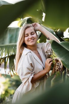 Exotic tropical woman near green leaves of banana bush. Tropical island girl on vacation