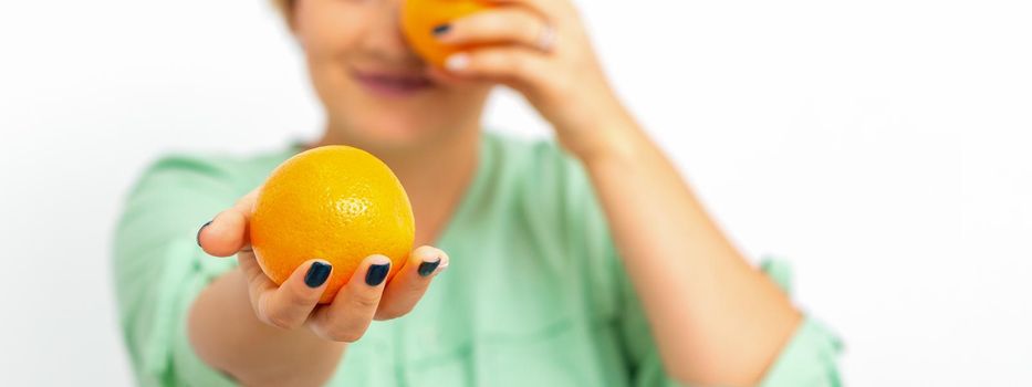 Smiling female nutritionist holding a whole orange, offering and looking at camera over white background, healthy diet concept