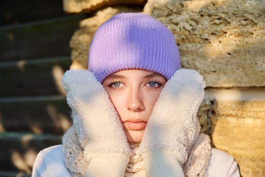 Portrait of young teenage woman in winter knitted hat scarf mittens, beautiful female looking at camera. Winter season, beauty, fashion, New Year Christmas holidays