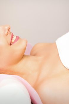 A beautiful smiling young woman is lying on a massage couch waiting for a massage in a massage room