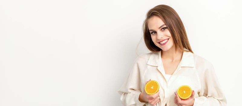 Young Caucasian smiling woman holding slices orange over isolated white background, breast health concept