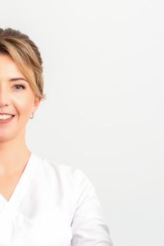 Close-up portrait of young smiling female caucasian healthcare worker standing staring at the camera on white background