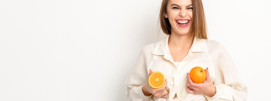 Young Caucasian smiling woman holding slices orange over isolated white background, breast health concept