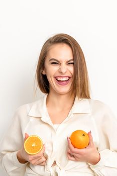 Young Caucasian smiling woman holding slices orange over isolated white background, breast health concept