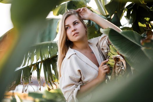Exotic tropical woman near green leaves of banana bush. Tropical island girl on vacation