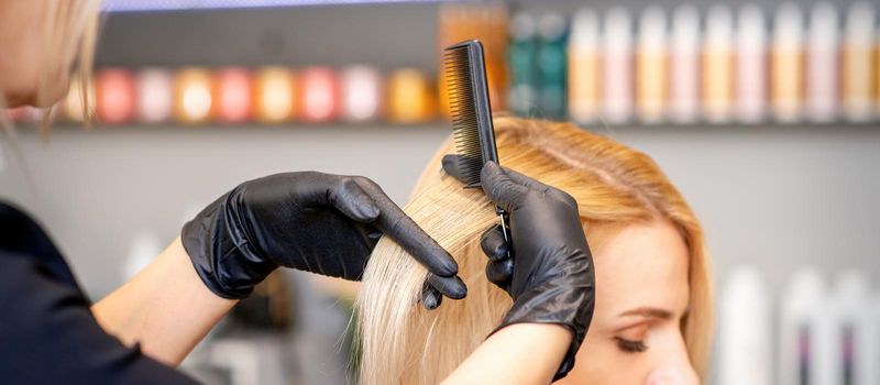 Beautiful young blonde woman with long straight blonde hair getting a haircut at the hairdresser salon