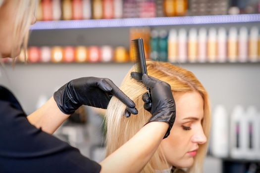 Beautiful young blonde woman with long straight blonde hair getting a haircut at the hairdresser salon