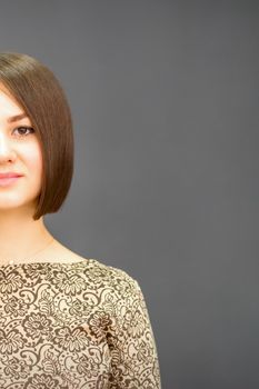 Beautiful young caucasian brunette woman with short hairstyle smiling and looking at camera against dark gray background with copy space