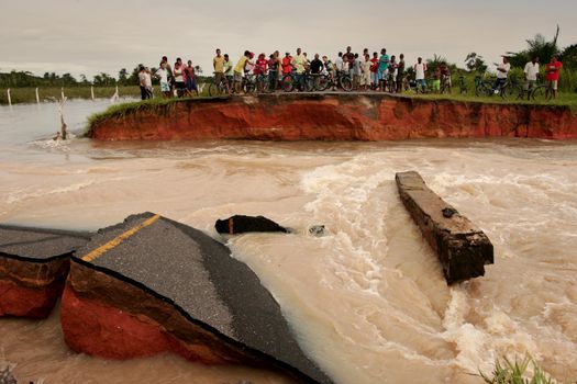 prado, bahia, brazil - april 7, 2010: people trying to cross a road destroyed due to flooding of a river in the city of Prado