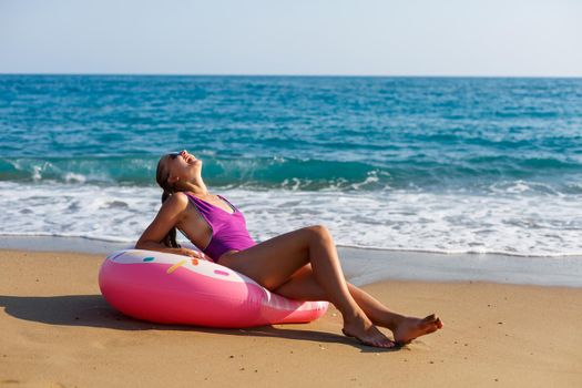 Woman on vacation on the beach relaxing in an inflatable ring on the ocean beach in travel. Girl in a swimsuit on the seashore in Turkey
