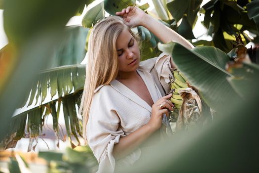 Exotic tropical woman near green leaves of banana bush. Tropical island girl on vacation