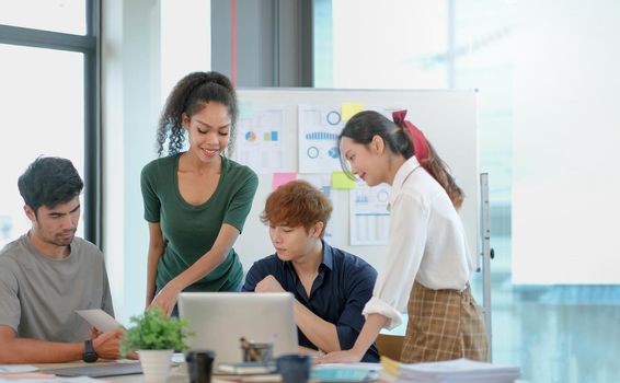 Group of young asian business people in smart casual wear working together in creative office using laptop..