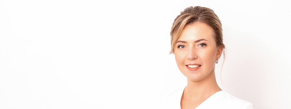 Close-up portrait of young smiling female caucasian healthcare worker standing staring at the camera on white background