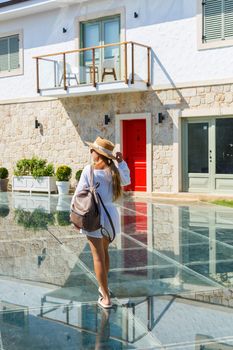 A young slender tanned woman in white shorts and a T-shirt, wearing sunglasses and a hat. Walk on a hot sunny day in the ancient city