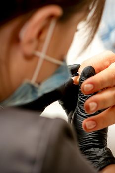 Manicure painting process. Manicure master paint the nails with transparent varnish in a nail salon, close up