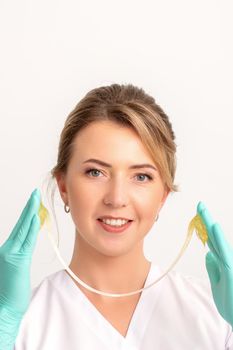 Young caucasian smiling female beautician holding wax for depilation over white background. Yellow sugar paste in hands master of depilation. Epilation concept