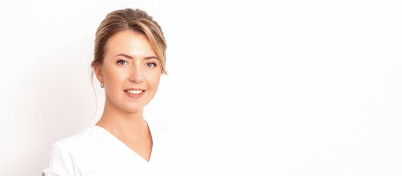 Close-up portrait of young smiling female caucasian healthcare worker standing staring at the camera on white background